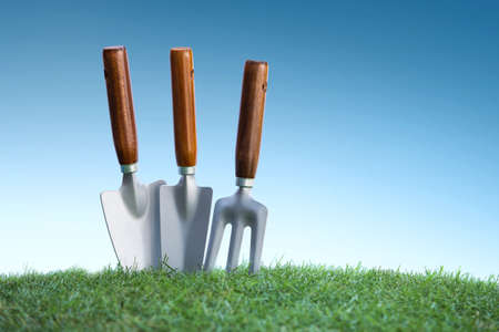 still life of close up gardening tools on green grass under bright blue skyの写真素材