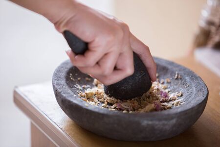 A portrait of a hand pounding herbs on a traditional pounderの写真素材