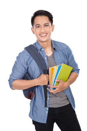 A portrait of a young asian student with a backpack on and holding booksの写真素材