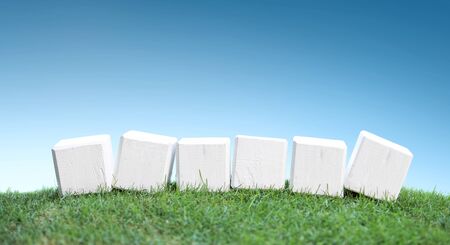 still life portrait of wooden blocks on a green grass under the bright blue sky, ready for your textの写真素材