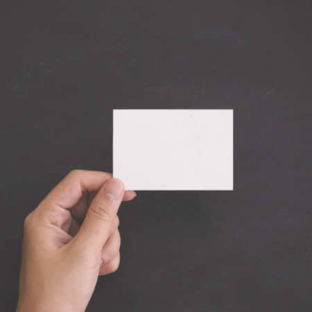A portrait of Hand holding a blank white card. black background. Mock Upの写真素材