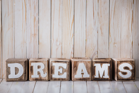 A portrait of DREAMS sign made of wooden blocks on wooden backgroundの写真素材