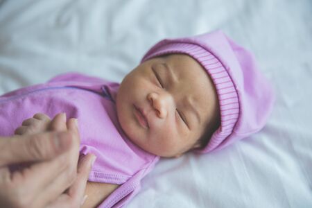 A portrait of newborn baby, holding her mother finger, close upの写真素材