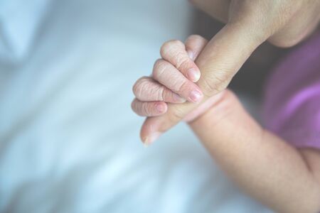 A portrait of newborn baby finger holding her mother, close upの写真素材