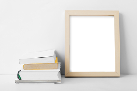 portrait of desk blank photo frame nest to stack of books with copy space on white backgroundの写真素材