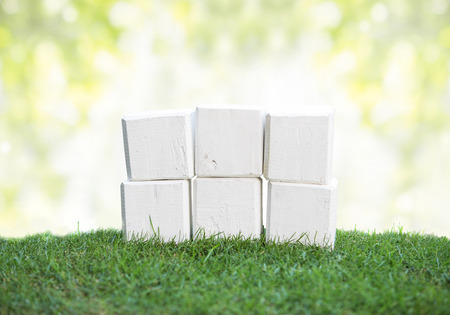 close up still life portrait of wooden blocks on a green grass, ready for your text with bokeh backgroundの写真素材