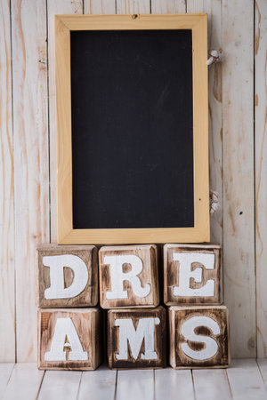 A portrait of chalkboard and DREAMS sign made of wooden blocks on wooden background