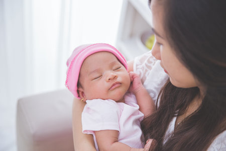 Asian woman holding her sleeping baby girl, close up