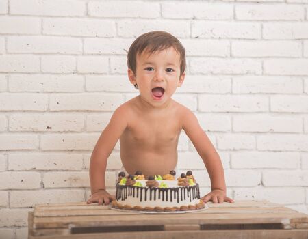 A portrait of a cute caucasian boy scream in front of a cakeの写真素材