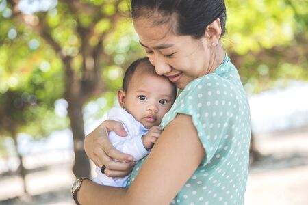 Portrait of a Woman holding her baby girl oudoorの写真素材