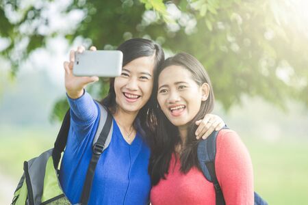 A portrait of two young Asian students taking selfie, happilyの写真素材