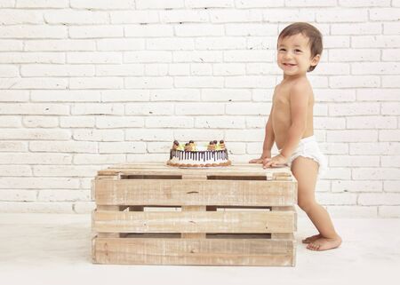 portrait of adorable toddler smiling with cake on wooden boxの写真素材