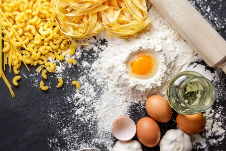 portrait of raw homemade italian pasta and ingredients on black boardの写真素材