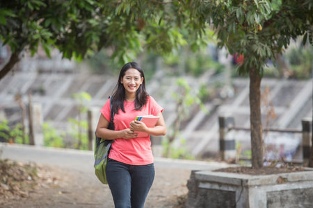 portrait of Young Asian student outdoor walking while holding her book
