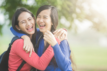 A portrait of happy two young Asian students laugh, joking around togetherの写真素材