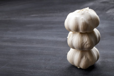 stack of three garlic on black board for table with copy space
