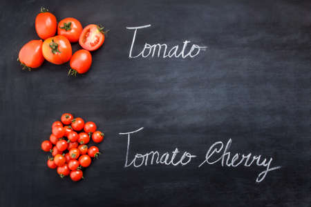 portrait of fresh tomatoes and tomato cherries on black board with inscriptionsの写真素材