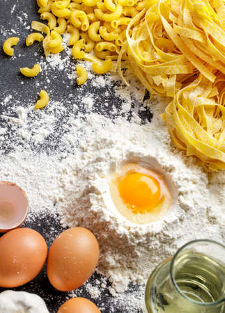 close up portrait of raw homemade italian pasta and ingredients on black boardの写真素材