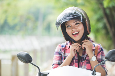A portrait of a young asian woman wearing a helmet before riding a motorcycle on a park