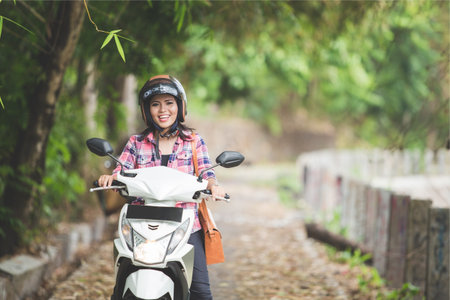 A portrait of a young asian woman riding a motorcycle in a park