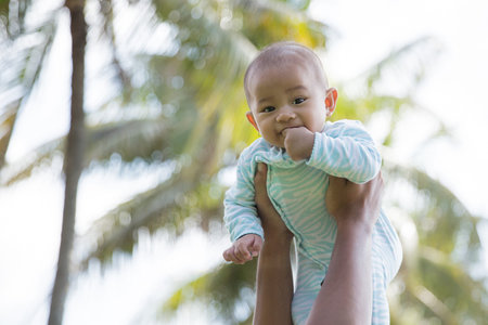 portrait of happy baby being raised to the air by her daddy