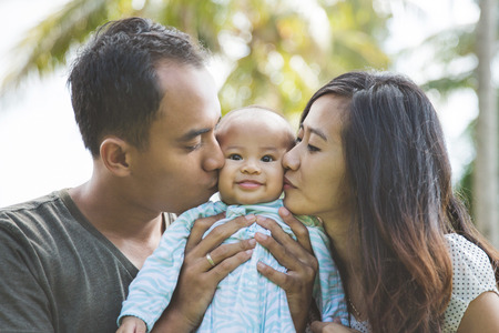 portrait of a beautiful asian young family having fun with his baby on a sunny dayの写真素材