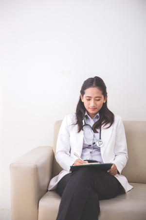 A portrait Young asian Female doctor, writing on a clipboardの写真素材