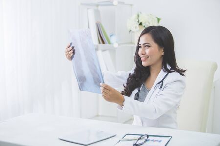 Female doctor looking at an x-ray in her officeの写真素材