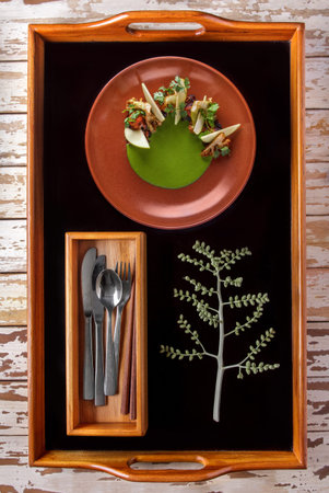 full portrait of octopus barbeque served with slice of apple, broccoli and green sauces on trays
