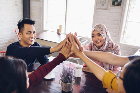 portrait of asian friend giving high five at cafe