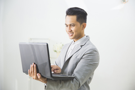Business man with a laptop over white backgroundの写真素材