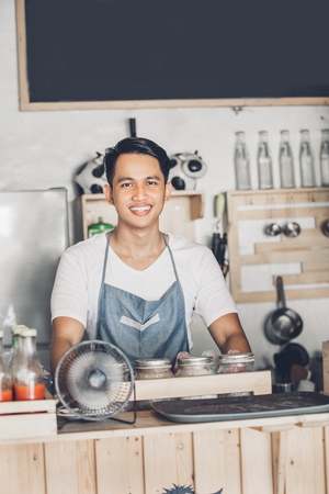 portrait of young cafe staff at work standing and smiling to cameraの写真素材