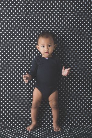little baby girl sitting on the floor isolated on a white backgroundの写真素材