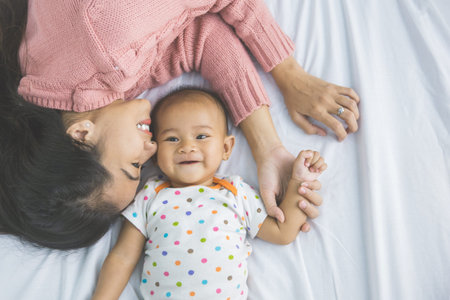 A portrait of a Young mother laying with her baby on bed
