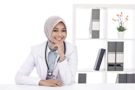 portrait of asian female doctor with stethoscope sitting and smiling at officeの写真素材