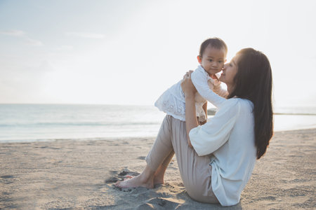 Portrait of mother and baby playing in the beach at sunset