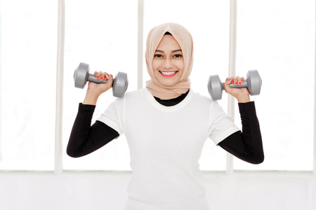 portrait of beautiful asian sporty woman lifting dumbbellsの写真素材