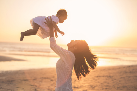 Portrait of mother and baby playing in the beach at sunsetの写真素材