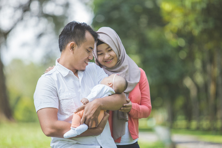 portrait of Beauty Mother and father with their newborn baby in the parkの写真素材