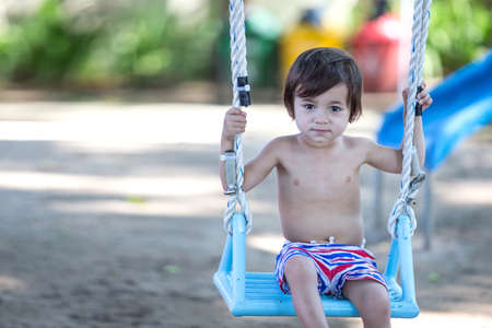 portrait of adorable little boy swinging in the parkの写真素材