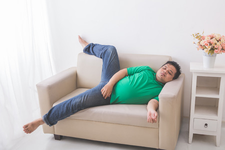 portrait of lazy Fat obese man sleeping on the couchの写真素材