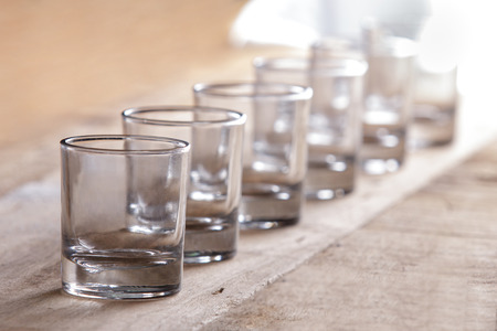 close up portrait of a group of shot glasses in a row on wooden backgroundの写真素材