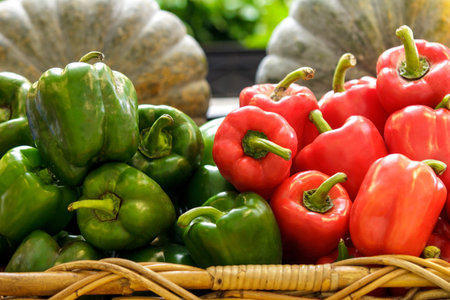 close up portrait of a group of fresh green and red bell peppers in a basket at supermarket