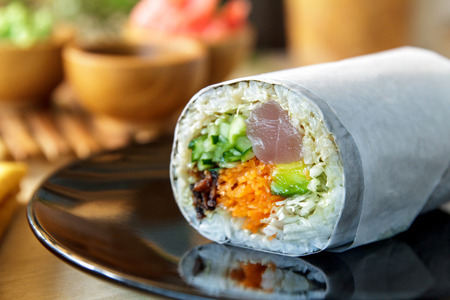 close up portrait of sushi burrito roll on shiny black plateの写真素材