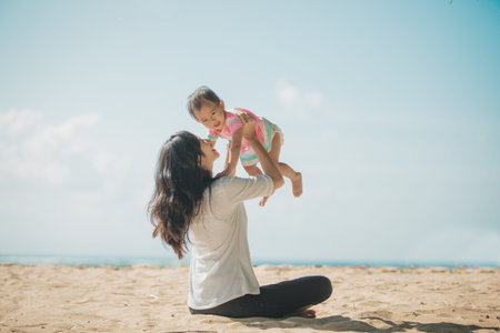 portrait of Happy mother and baby girl playing at seaside