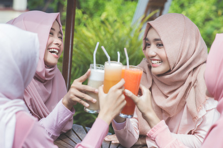 portrait of pretty asian muslim woman having fun in cafe together with friendsの写真素材