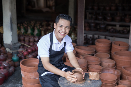 craftsman artist making pottery vase from fresh wet clay on pottery wheelの写真素材
