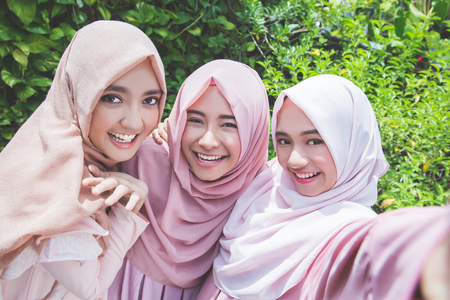 asian girl friends with head scarf taking selfie togetherの写真素材