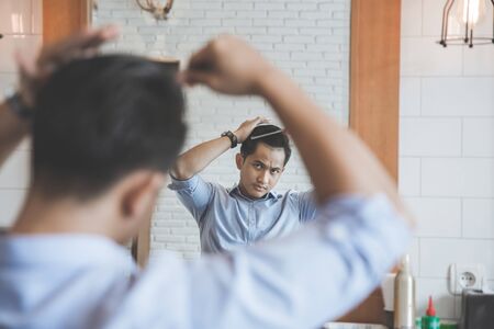 portrait of man combing his hair after having a cut at barbershopの写真素材