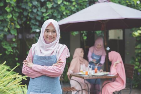 portrait of proud young business owner standing in front of her cafe. customer sitting at the backgroundの写真素材
